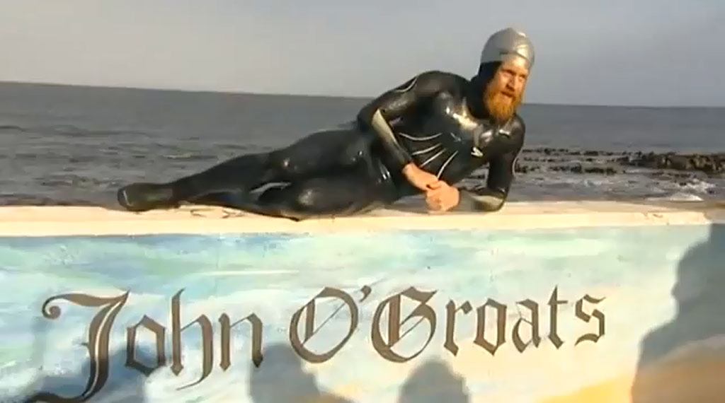 Sean Conway lays on a John O’Groats sign for a camera.