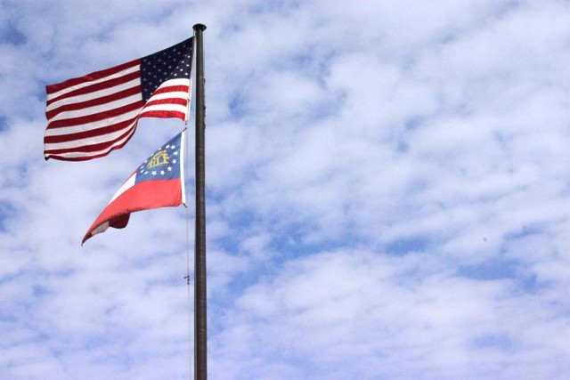 The flag of the United States flies above the flag of the US State of Georgia on a flagpole. According to US law regarding the handling of flags, the US flag must fly above a sub-national flag on a flagpole. The US flag and the flag of any other sovereign country must be placed beside each other on flagpoles of equal size.