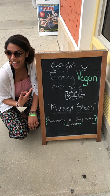 Leilani, a vegan, sitting in front of an anti-vegan sign. She and her friends laughed as she posed for the photograph.
