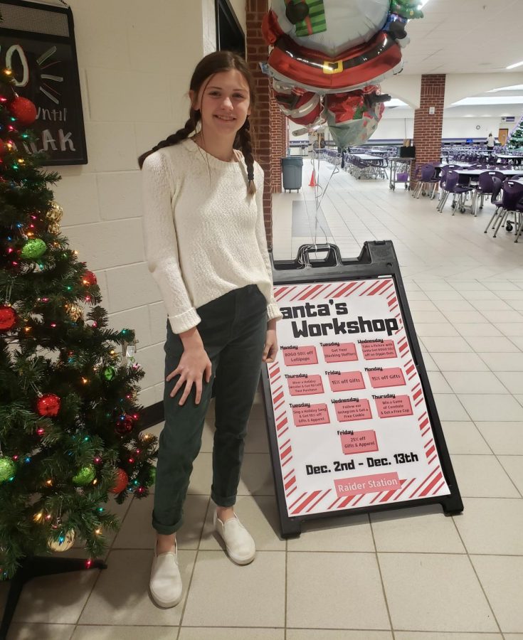The Raider Station has created a two-week-long event called “Santa’s Workshop” to claim discounts on school apparel this holiday. This is sophomore Bailey Sanders (a school store employee) standing in front of the discount calendar.