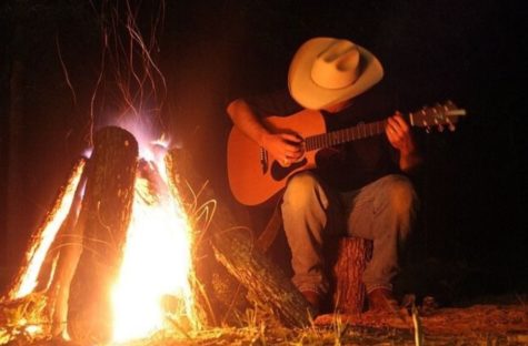  A cowboy sits next to a fire and plays the guitar on a cool summer night. Photo by WWBW.