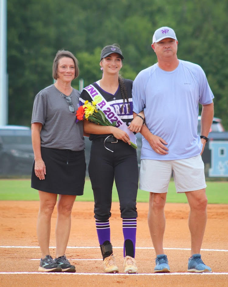 Shelby Morgan posing alongside her parents on senior night.