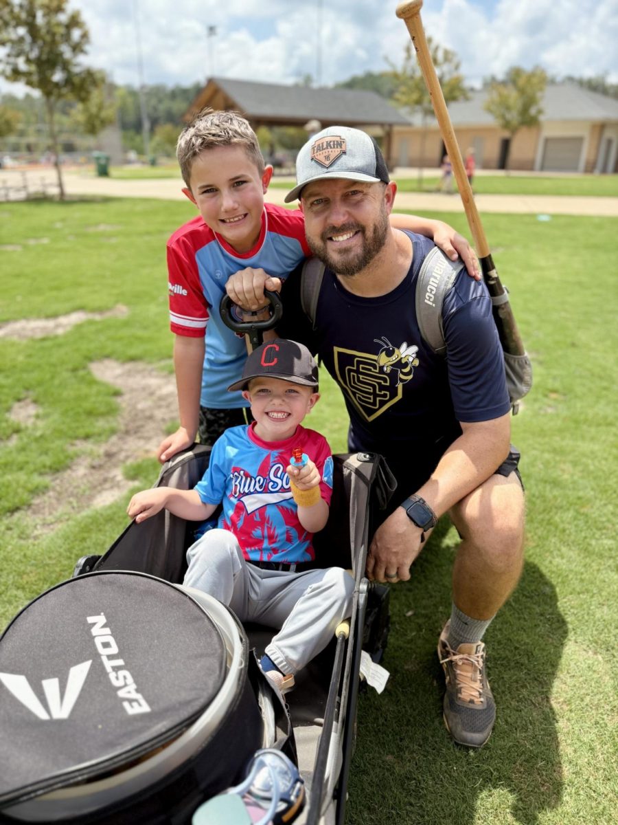 Philip Oliver coaching baseball along with his two sons by his side.