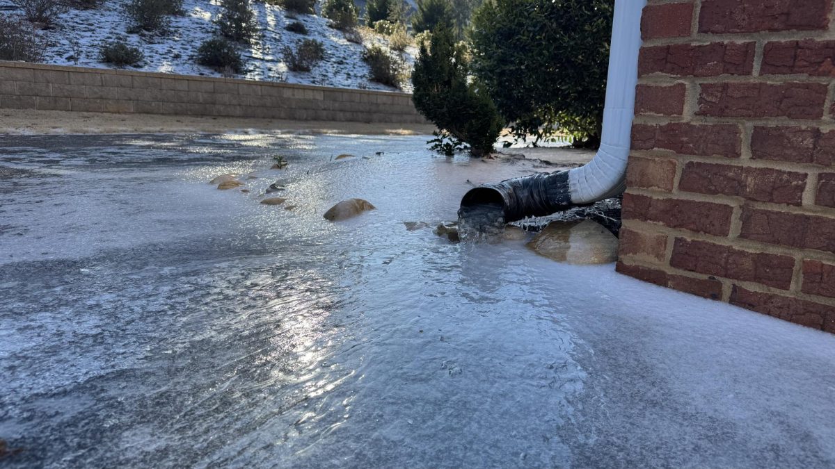A drainpipe and surrounding area completely frozen over.