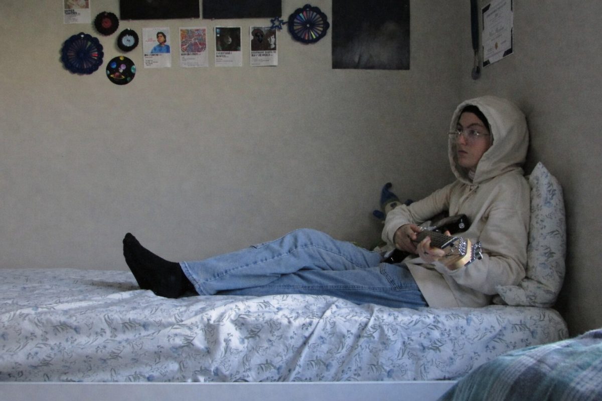 Me sitting on my bed playing my guitar while lost in thought.
